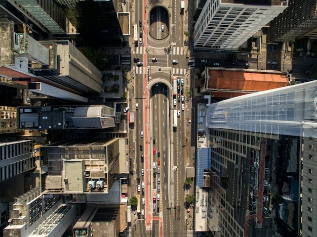 An elevated view of a modern light rail train moving through a city neighborhood. The train is sleek and the surrounding area is a mix of residential buildings and small businesses.