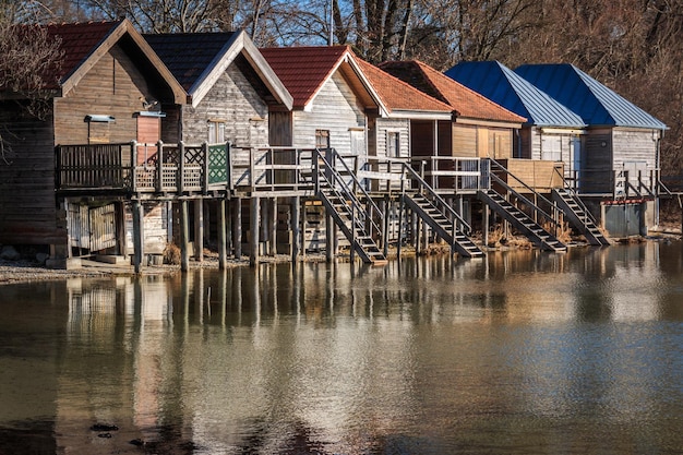 A flooded street in a coastal town, with houses submerged in water. A few people are wading through the water, some with boats. The sky is overcast and dark, illustrating the devastating impact of climate change on communities.