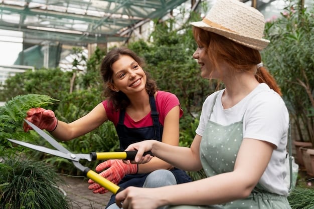 Two young people are working together on a community garden project with the guidance of a mentor. They are laughing and engaged in the activity.