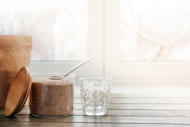 An open container of collagen powder next to a glass of water and a spoon. The powder is white, and the scene is set in a brightly lit kitchen to showcase a typical morning routine.
