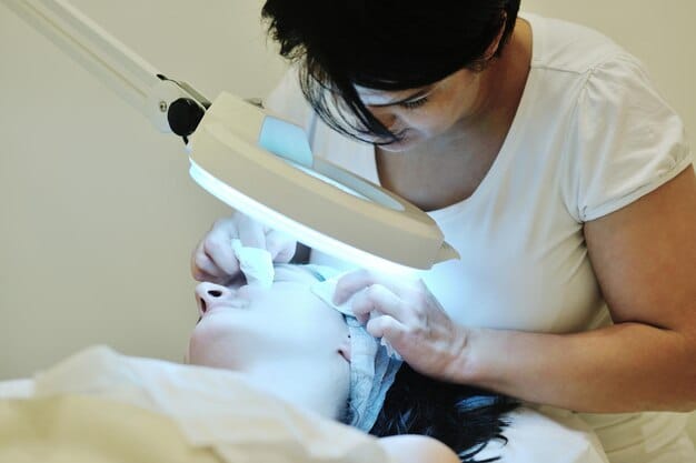 A dermatologist carefully performing a laser skin resurfacing procedure on a patient's forehead, focusing on the precision of the laser's application. The setting is a modern, sterile clinic.