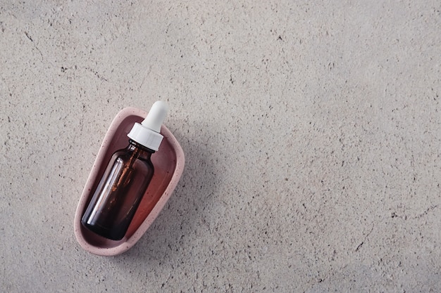 A sleek, amber-glass dropper bottle of Skinceuticals CE Ferulic serum, placed next to a small dish of fresh oranges and a health supplement bottle, suggesting a combination of topical and internal nutrition.
