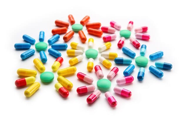 Various colorful supplement pills and capsules displayed neatly on a white background, suggesting a regimen of anti-aging supplements.