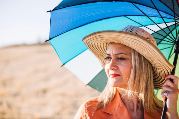 A person wearing a wide-brimmed hat and sunglasses, sitting under an umbrella on a sunny day, showcasing multiple sun protection methods.