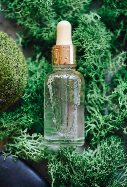 A close-up of a clear glass bottle of Niacinamide serum with a dropper, highlighting its smooth texture against a backdrop of soft, blurred botanical elements.